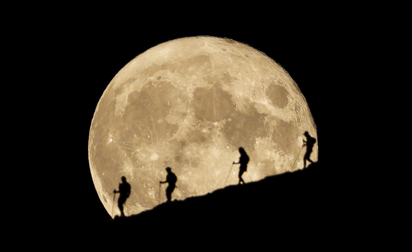 Runners descnding in front of full moon